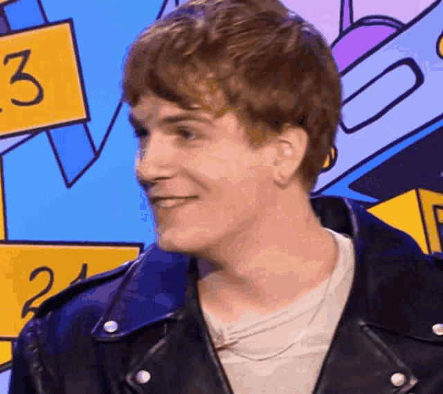 a man wearing a black leather jacket is smiling in front of a sign that says ' 3 '