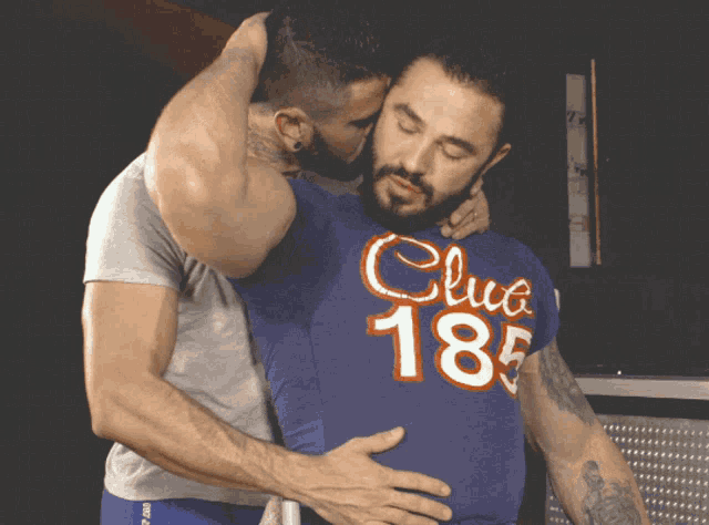 two men are hugging and one has a shirt that says club 185 on it