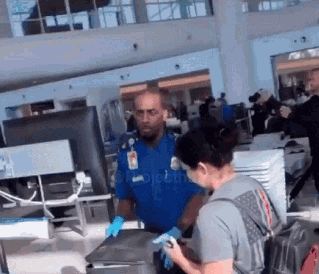 a man wearing a name tag that says ' security ' on it is talking to a woman