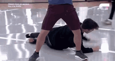 a man is laying on the floor while another man stands on top of him .