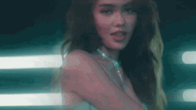a close up of a woman wearing a necklace and a white dress in a dark room .