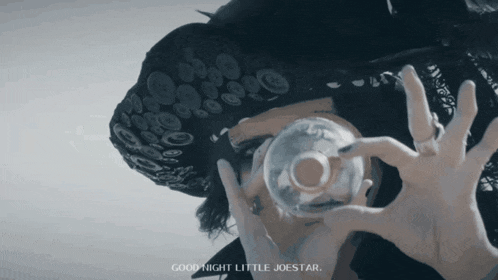 a person holding a glass with the words good night little joestar written on the bottom