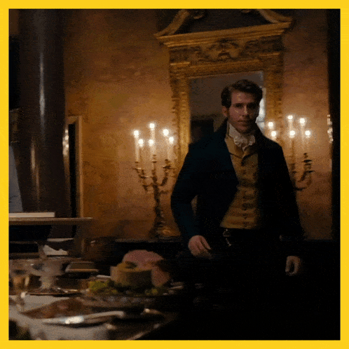 a man in a suit stands in front of a table with candles
