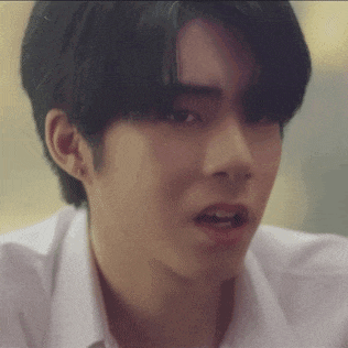 a close up of a young man 's face with a white shirt on making a funny face .