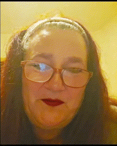 a woman wearing glasses and a headband looks at the camera with her eyes closed