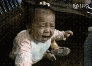 a baby girl is crying while sitting on a wooden bench .