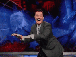 a man in a suit is dancing in front of a screen