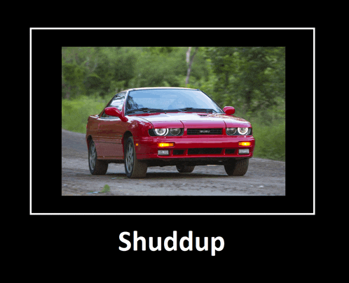 a picture of a red car on a dirt road with the word shuddup below it