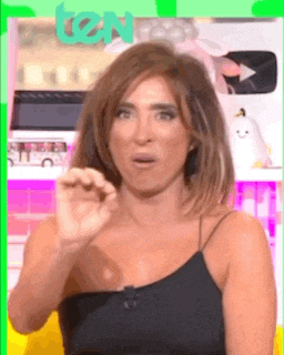 a woman in a black tank top is making a funny face and making a hand gesture .