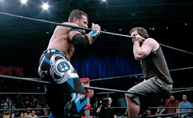 two men are wrestling in a ring with one wearing a pair of shorts that say j.j.