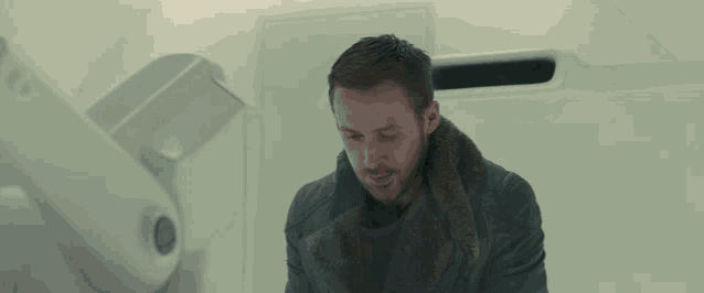 a man in a black jacket is laughing in front of a white box