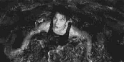 a black and white photo of a woman crawling through the water .