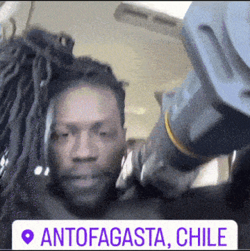 a man with dreadlocks is standing next to another man with dreadlocks and a sign that says antofagasta chile