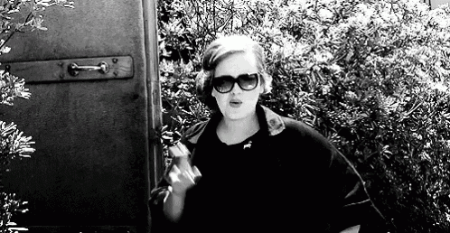 a black and white photo of a woman wearing sunglasses and a black jacket .