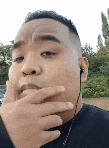 a man wearing earbuds looks at the camera