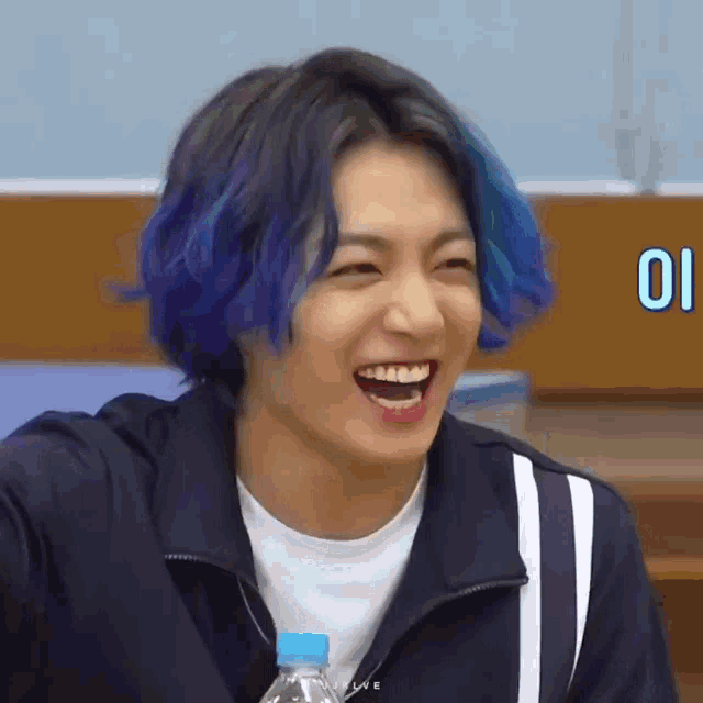 a close up of a person with blue hair laughing with a bottle of water .