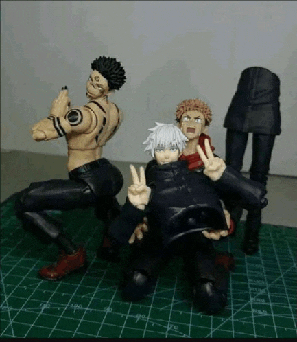 a group of action figures are posing for a picture on a green cutting mat .