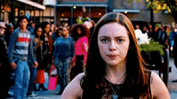 a woman stands in front of a crowd of people on a city street