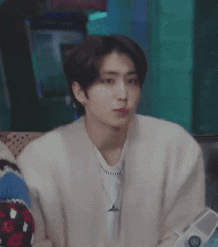 a young man in a white sweater is sitting on a couch .