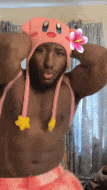 a shirtless man wears a pink kirby hat