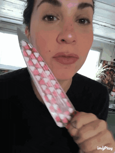 a woman holding a knife with pink hearts on it