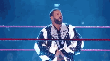 a shirtless wrestler is in a wrestling ring with his arms outstretched .