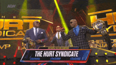 a man in a suit is holding a trophy with the words the hurt syndicate on the bottom