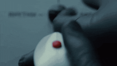 a person is pressing a red button on a white mouse
