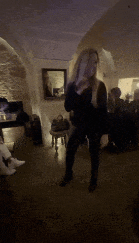 a woman dancing in a dark room with a mirror in the background