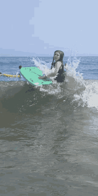 a young girl is riding a wave on a green boogie board that says ' hawaii ' on it