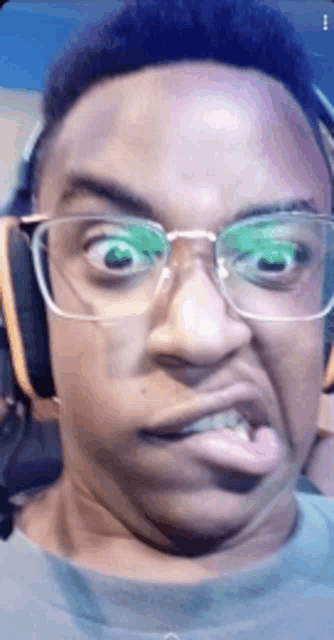 a man wearing glasses and headphones is sticking his tongue out .