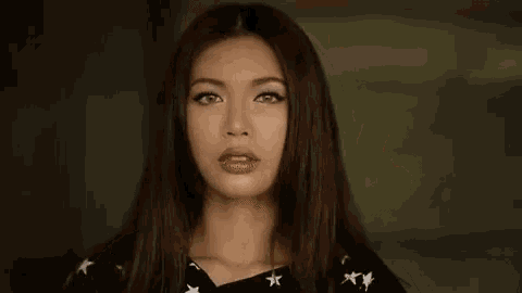 a woman is making a funny face and pointing her finger .