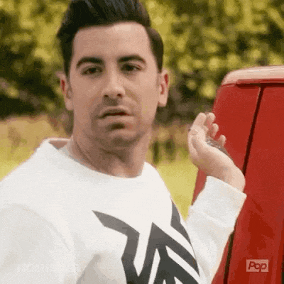 a man in a white shirt is standing next to a red van .