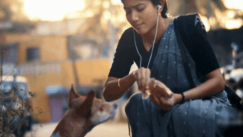 a woman wearing ear buds looks at a dog