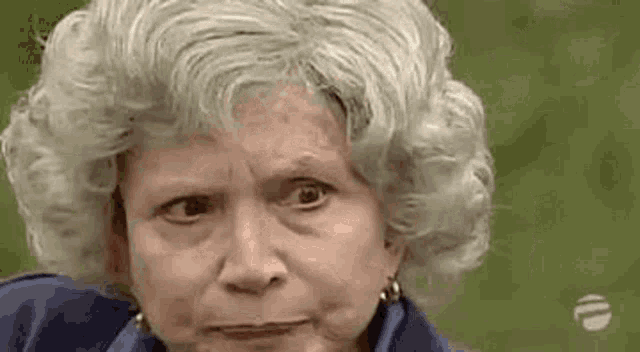 an elderly woman with gray hair and earrings is making a funny face .