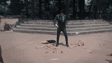 a man in a suit and tie is standing on a pile of money on the ground with the word un9ty below him