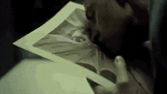 a man is holding a piece of paper in his hand and looking at it .