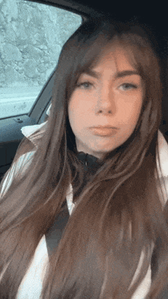 a woman with long brown hair is sitting in a car .