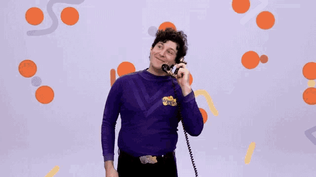 a man in a purple wiggle shirt talking on a phone