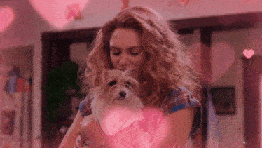 a woman is holding a small dog in her arms