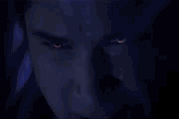 a close up of a man 's eyes with glowing red eyes in the dark .