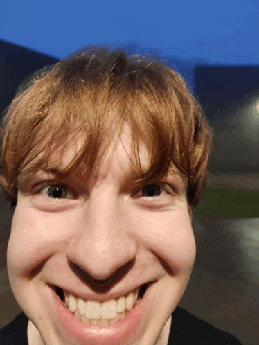 a close up of a young man 's face with a big smile on his face