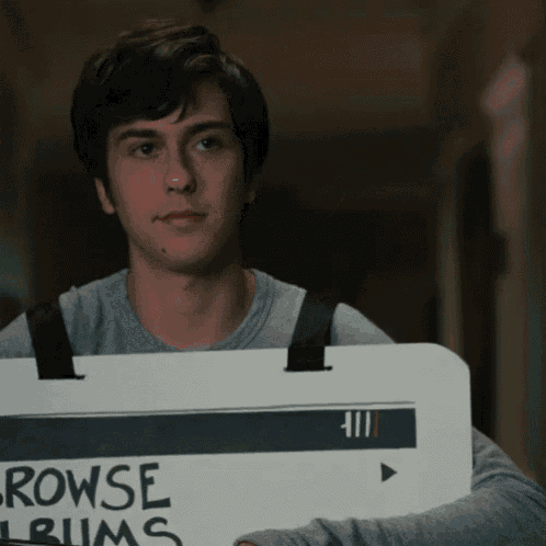 a young man is holding a sign that says " browse albums "