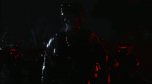 a group of soldiers are standing in a dark room with red lights behind them