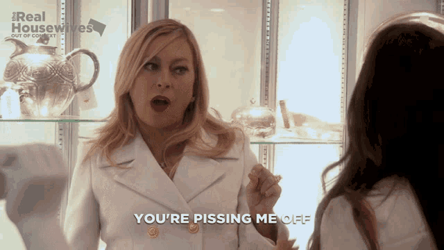 a woman says you 're pissing me off in front of a real housewives sign