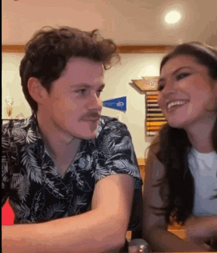 a man and a woman are looking at each other while sitting at a table .