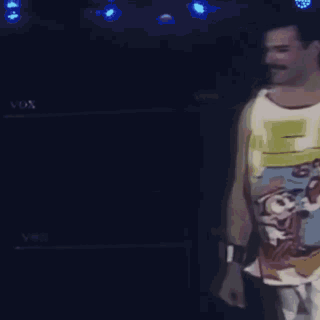 a man wearing a mickey mouse tank top is dancing on stage