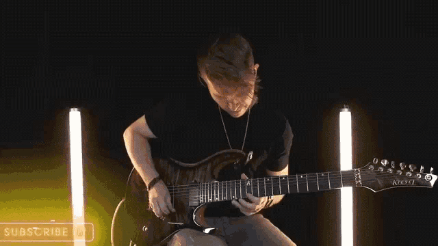 a man is playing an electric guitar in a dark room with lights behind him .
