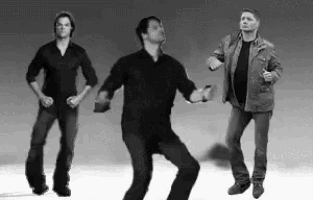 three men are standing next to each other dancing in a black and white photo .