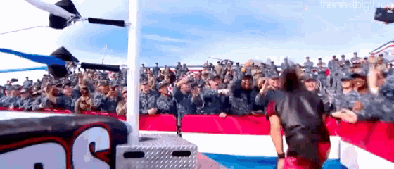 a wrestling match is taking place in front of a large crowd of soldiers .